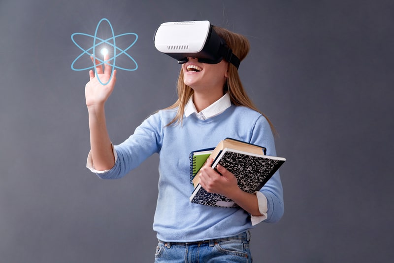 Learner wearing a virtual reality headset and holding notebooks during an interactive e-learning experience.